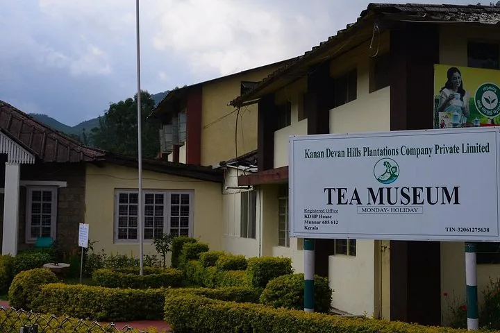 Letrero del Museo del Té de Kanan Devan Hills Plantations en el exterior de un edificio amarillo pálido